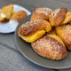 Plate of half a dozen orange-tinged rolls covered in sesame seeds